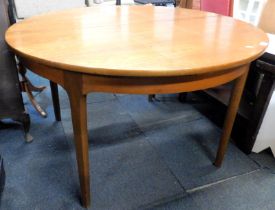 A mid century teak extending dining table, the circular top raised on tapering legs, 75cm high, the
