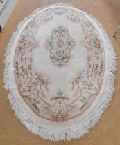 A Chinese wool oval cream ground rug.