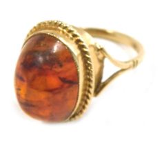 A 9ct gold imitation amber dress ring, the raised polished cabochon amber style stone in a rope twis