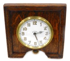 A 1920s/30s oak cased travel clock, the square set dial with brass white enamel numeric baton, with