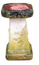 A reconstituted stone bird table, the square design top on a column decorated with birds and berries