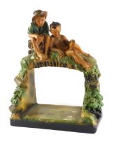 An early 20thC Chalkware centrepiece, modelled in the form of two boys seated above an arched alcove