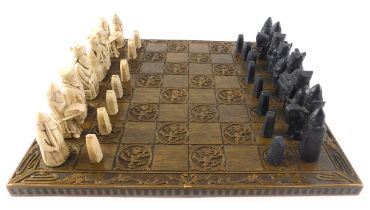 A chess set, with medieval style resin pieces, the oak board carved with heraldic dragons, etc., 45c