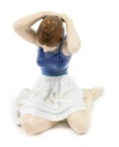 A Royal Copenhagen porcelain figure modelled as a lady seated adjusting hair, printed marks number 4