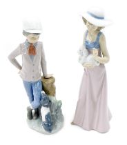 Two Nao porcelain figures, modelled as lady holding dog, and young boy leaning against tree stump be