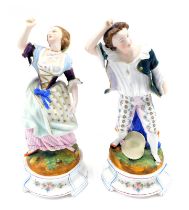 A pair of late 19thC German bisque porcelain figurines, modelled in the form of a gentleman and lady