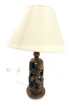 An African carved hardwood tribal table lamp base, decorated with figures, etc., and a cream shade,