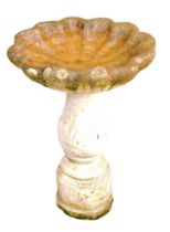 A reconstituted stone scallop shaped bird table, on a reeded acanthus leaf column, on hexagonal base