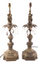 A pair of Continental gilt metal table lamps, each with cut glass drops and modelled with putti, lea