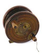 A mahogany and brass star backed fly fishing reel, 8cm diameter.