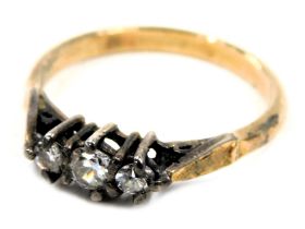 A three stone dress ring, set with three white paste stones in claw setting, on a gold coloured band