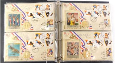 An album of 1996 Olympic Games first day coin covers, each inset with a gold medallion and signed by