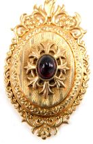 An Edwardian 9ct gold pendant and chain, the oval locket set with cabochon ruby, with scroll and eng