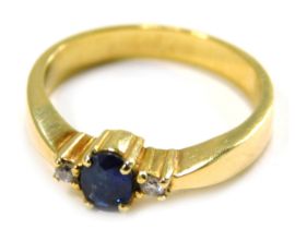 A sapphire and diamond three stone ring, set with oval sapphire in four claw setting, flanked by two