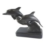 A cast bronze sculpture of two dolphins on a wave, on a rectangular plinth, unsigned, 30cm high.