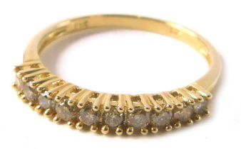 A diamond half hoop dress ring, set with twelve tiny diamonds, each in claw setting, on a thin yello