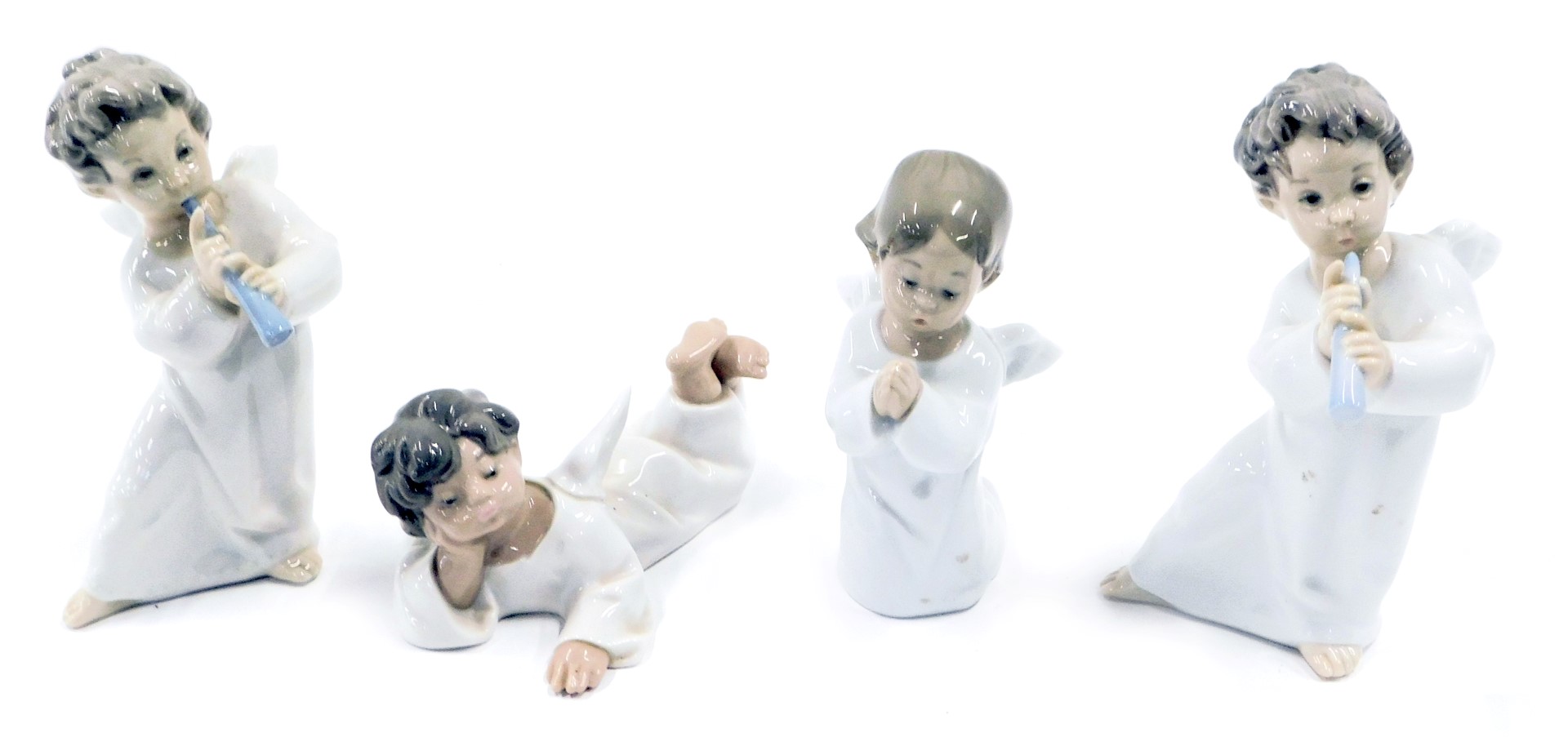Four Lladro porcelain figures modelled as angels, in various poses, two playing a wind instrument, o