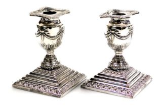 A pair of Edwardian Adam style silver plated candlesticks, of urn form, embossed with swags and acan