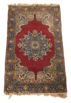 A Kirman red ground rug, with a central floral medallion within repeating floral borders, 152cm x 95