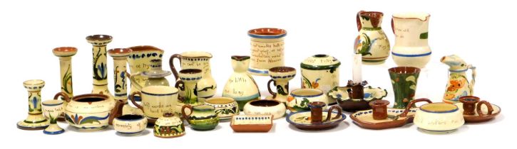 A group of Devon Motto Ware pottery, including candlesticks, hair tidy, chamber sticks, tea cup and