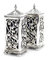 A pair of Edward VII Art Nouveau silver pepperettes, with blue glass liners, the sides pierced and e