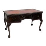 A Georgian style mahogany serpentine desk, with a gilt red tooled red leather top, above one long an