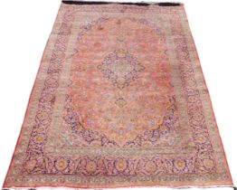 A Kashan pink and purple ground rug, the central field decorated with stylised floral medallions and
