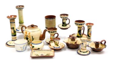 A group of early 20thC Devon Motto Ware pottery, including candlesticks, chamber sticks, a teapot an