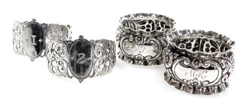 A pair of Victorian silver napkin rings, with pierced and foliate decoration, with oval reserves num