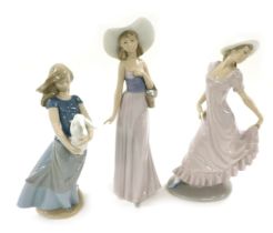 Three Nao porcelain figures of young ladies, one in a pink dress, another holding a rabbit, the thir