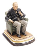 A Capodimonte porcelain figure of Winston Churchill, by B. Merli, model seated in an armchair, holdi