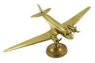 A brass desk stand, modelled as a Douglas Dakota airplane, raised on a circular base 37.5cm wide.