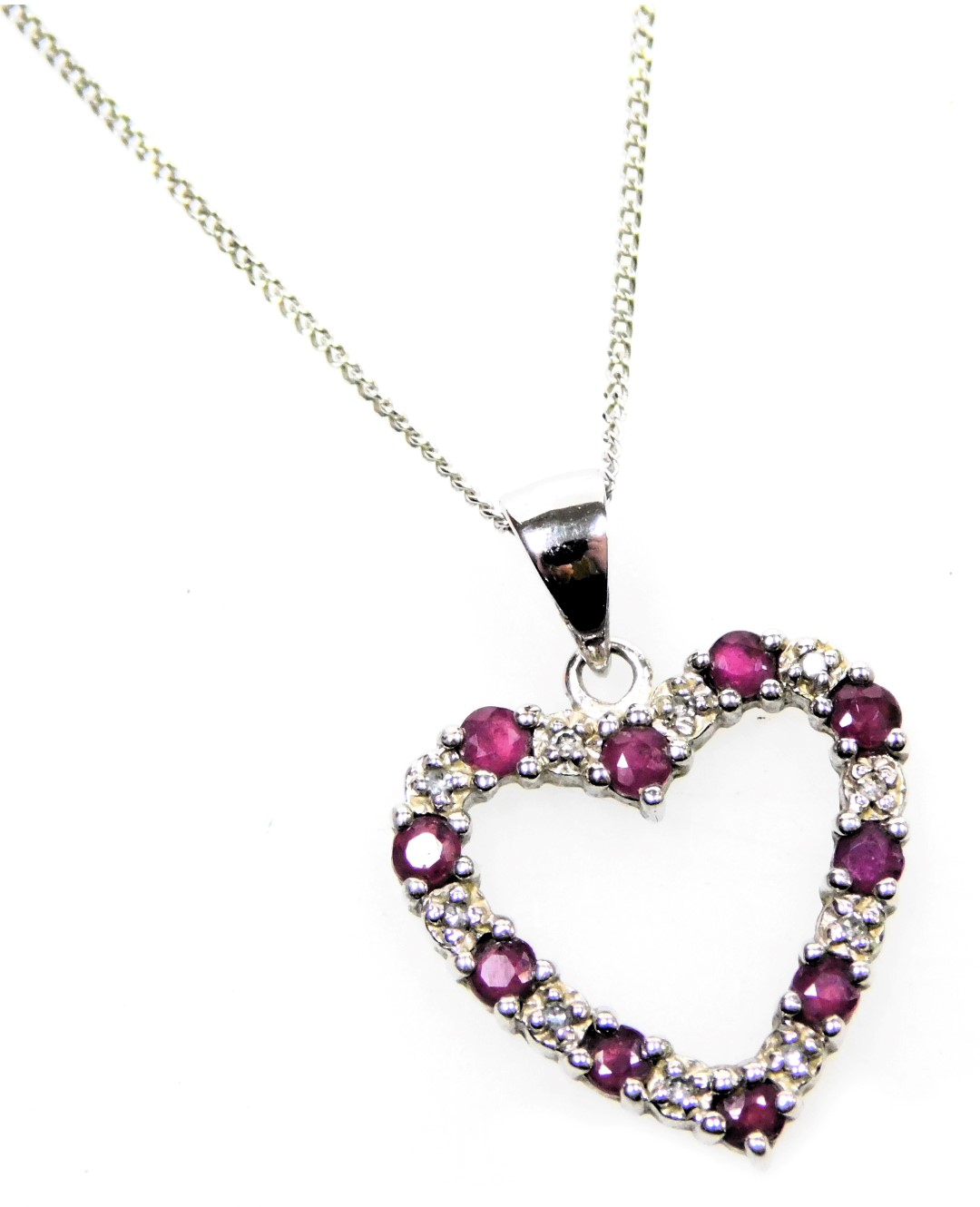 A 9ct white gold ruby and diamond heart shaped pendant, on a ring suspension, and fine curb link nec