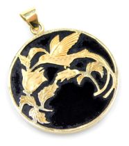 A circular black onyx pendant, overlaid in yellow metal with a humming bird drawing nectar from flow