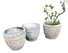 Three concrete plant pots, moulded with fruit, one containing a rose, 28cm high.