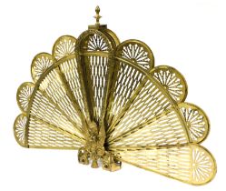 A brass folding fan shaped fire guard, of peacock form, 63cm high.