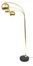 A brushed polished brass three branch uplighter, raised on a circular black base, 190cm high.