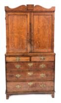 A George III oak linen press, with a shaped pediment over a pair of panelled doors enclosing shelves