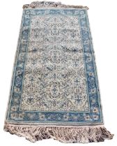 A Tunisian cream ground rug, the central field decorated with floral motifs within a repeating flora