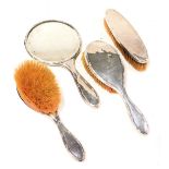 A George V silver backed four piece dressing table set, comprising a pair of hair brushes, clothes b