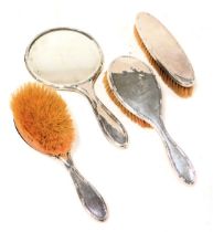 A George V silver backed four piece dressing table set, comprising a pair of hair brushes, clothes b