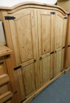 A pine three door wardrobe, raised on a plinth base.