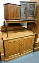 An oak two door cupboard with shelves to interior, two smoker's cabinets and a glass topped coffee t