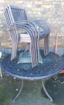 A metal garden table set, including five chairs, parasol base and circular table.