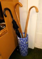 A blue and white Oriental style stick stand with two walking sticks and two umbrellas.