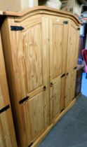 A pine triple door wardrobe, raised on a plinth base.