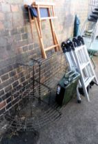 A set of aluminum ladders, metal framed planting steps, a jerry can and a wooden director's chair.