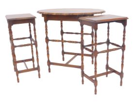 A 20thC nest of three tables, the oval shaped top raised on turned legs united by turned and straigh
