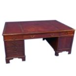 An Edwardian mahogany partner's desk in George III style, with a tooled red leather top, each side w