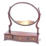 A 19thC swing frame toilet mirror, the oval mirror mounted on two scroll supports, on a shaped base,